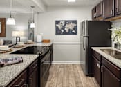 Thumbnail 7 of 33 - A kitchen with a black fridge and wooden floors.