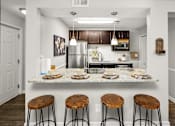 Thumbnail 10 of 33 - A kitchen with a granite countertop and bar stools.