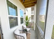 Thumbnail 17 of 23 - A balcony with a chair and table.