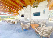 Thumbnail 9 of 23 - A patio with a stone fireplace and a TV mounted on the wall.