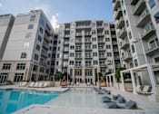Thumbnail 29 of 36 - Luxury Apartments Near Piedmont Park, Midtown Atlanta, GA - Trace Midtown - Swimming Pool With Poolside and Submerged Loungers, Cabanas, and View of Apartment Complex.