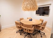 Thumbnail 5 of 36 - A conference room with a round table and chairs.