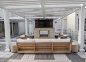 Thumbnail 25 of 36 - A wooden sofa is on a patio with a television on the wall.