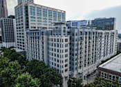Thumbnail 1 of 36 - A large building with many windows is surrounded by trees.