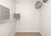 Thumbnail 9 of 36 - A room with a carpeted floor, a white wall, and a metal shelf with two storage boxes.