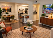 Thumbnail 1 of 20 - A living room with a dining table and chairs, a sofa, a coffee table, and a television displaying the Peachtree logo.