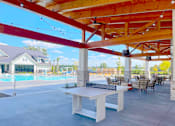 Thumbnail 10 of 23 - A patio with a table and chairs under a wooden pergola.