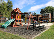 Thumbnail 16 of 24 - A playground with a green slide and a red wooden playhouse.