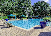 Thumbnail 1 of 31 - A pool surrounded by trees and a bench.
