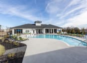 Thumbnail 19 of 22 - Dog-Friendly Apartments in Mauldin, SC - The Aster - Resort-Inspired Swimming Pool with Lounge Chairs, Umbrellas, and View of the Clubhouse.