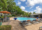 Thumbnail 1 of 38 - A pool area with sun loungers and a building in the background.