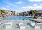 Thumbnail 14 of 18 - a large swimming pool with white chairs in front of an apartment building