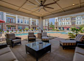 Thumbnail 5 of 53 - A patio with a table, chairs, and a pool in the background.