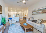 Thumbnail 3 of 40 - A living room with a white couch, a wooden coffee table, and a painting on the wall.