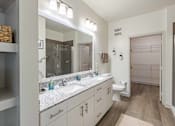 Thumbnail 7 of 40 - A bathroom with a sink, mirror, toilet, and a walk-in shower.