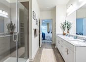 Thumbnail 8 of 40 - A bathroom with a walk-in shower and a vanity with a mirror.