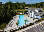 Thumbnail 16 of 27 - Luxury Apartments in Ridgeville, SC, with In-Unit Washer and Dryer - Preserve at Ridgeville - Resort Style Swimming Pool with In-Water Loungers, Tanning Chairs, Umbrellas, and View of the Clubhouse.
