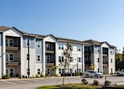 Thumbnail 20 of 27 - an apartment building with cars parked in front of it