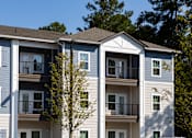 Thumbnail 21 of 27 - an apartment building with trees in the background