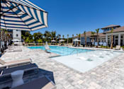 Thumbnail 21 of 40 - A large outdoor swimming pool surrounded by lounge chairs and umbrellas.