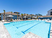 Thumbnail 20 of 40 - A large swimming pool with lane markers and a building in the background.