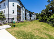 Thumbnail 33 of 40 - A large grassy area in front of a white apartment building.