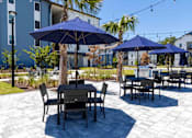 Thumbnail 22 of 40 - A patio with tables and chairs and umbrellas.