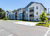 Thumbnail 40 of 40 - A large apartment complex with a parking lot in front.