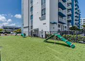 Thumbnail 31 of 35 - A playground with a green slide in front of a white building.