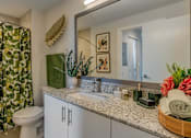 Thumbnail 23 of 35 - A bathroom with a white toilet, a green shower curtain, and a mirror.