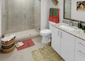 Thumbnail 27 of 35 - Dog-Friendly Luxury Apartments In Hialeah, FL - Pura Vida - Bathroom With Elegant And Modern Laminate Cabinetry, Porcelain Tile Flooring, Large Mirror With Vanity Light, Granite Countertop, And Standing Shower.