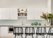 Thumbnail 9 of 35 - a kitchen with white cabinets and a counter with four chairs