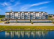 Thumbnail 29 of 30 - A large building with a grey facade is situated next to a body of water.