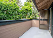 Thumbnail 14 of 48 - A balcony with a sliding door and a view of green trees.