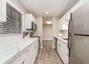 Thumbnail 17 of 48 - A kitchen with white cabinets and a black fridge.