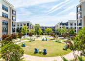Thumbnail 43 of 49 - a park with lawn chairs and trees in front of apartment buildings