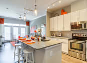 Thumbnail 16 of 49 - 1-Bedroom Luxury Apartments in Decatur, GA - Reserve Decatur - Kitchen with Stainless Steel Energy Star Appliances, Kitchen Island/Breakfast Bar with Barstools, Pendant Lights, Quartz Countertops, White Cabinets, and Subway Tile Backsplash.