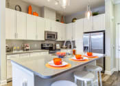 Thumbnail 15 of 49 - a kitchen with white cabinets and a counter with plates and cups on it