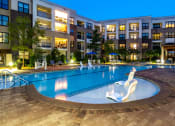 Thumbnail 46 of 49 - a swimming pool at night with an apartment building in the background
