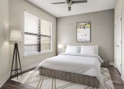 Thumbnail 30 of 49 - 1 Bedroom Luxury Apartments in Decatur, GA - Reserve Decatur - Bedroom With Designer Plank Flooring, Modern Ceiling Fan, Window With Vertical Blinds, Wall Art, and Floor Lamp. 