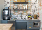 Thumbnail 3 of 25 - A kitchen with a wooden table in front of a blue and white tiled wall.