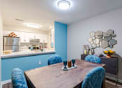 Thumbnail 10 of 25 - A kitchen with blue walls and a wooden table with blue chairs.