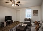 Thumbnail 4 of 24 - A living room with a grey couch, a brown coffee table, and a ceiling fan.