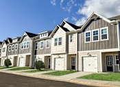 Thumbnail 8 of 56 - A row of houses with white garage doors and black shutters.