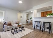 Thumbnail 1 of 28 - a living room with a couch and stools in front of a kitchen