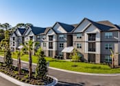 Thumbnail 25 of 32 - A large, modern apartment complex with a well-maintained lawn and landscaping.