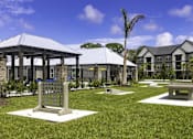 Thumbnail 23 of 32 - A gazebo is surrounded by benches and trees in a grassy area.