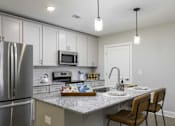 Thumbnail 2 of 32 - A modern kitchen with a stainless steel refrigerator and a granite countertop.