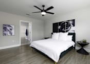Thumbnail 8 of 32 - A bedroom with a bed, a ceiling fan, and a wall art.