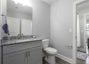 Thumbnail 10 of 32 - A bathroom with a toilet, sink, and mirror.